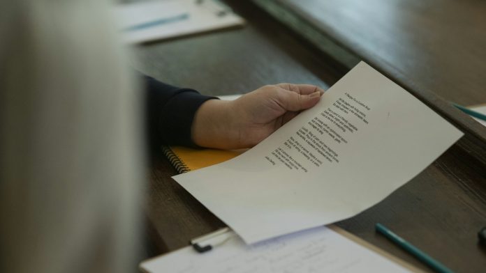 Ruka drži ispisani list papira iznad radnog stola