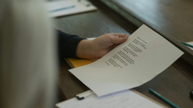 Ruka drži ispisani list papira iznad radnog stola