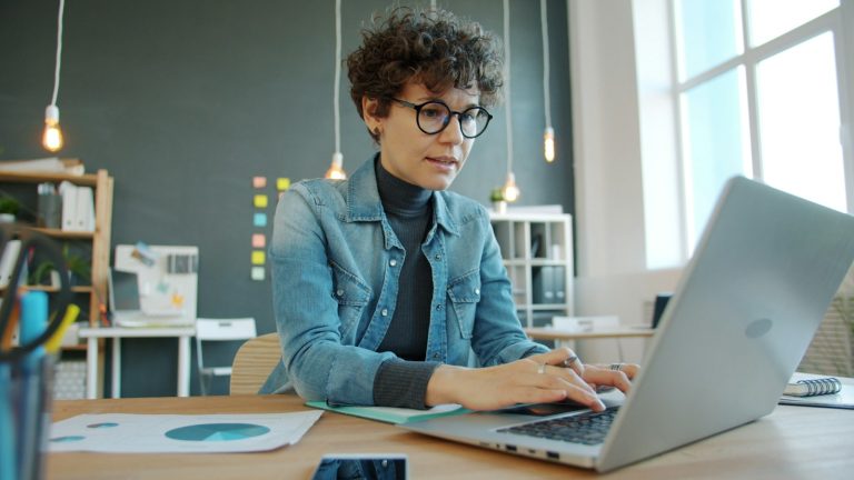 Žena koncentrirano radi na laptopu u modernom uredu